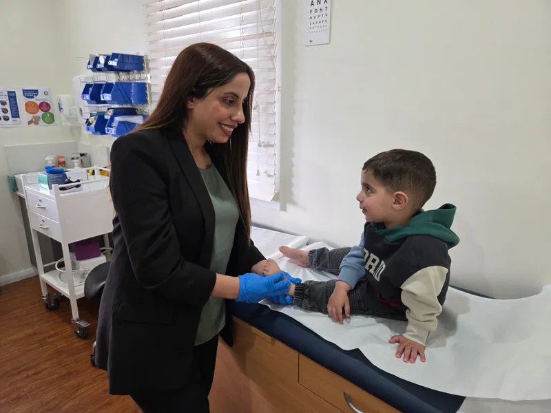 Madleen smiling with a young child during a foot care appointment